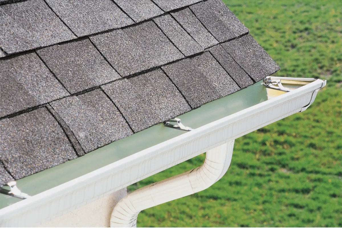 New seamless gutter installed along an asphalt shingle roofline